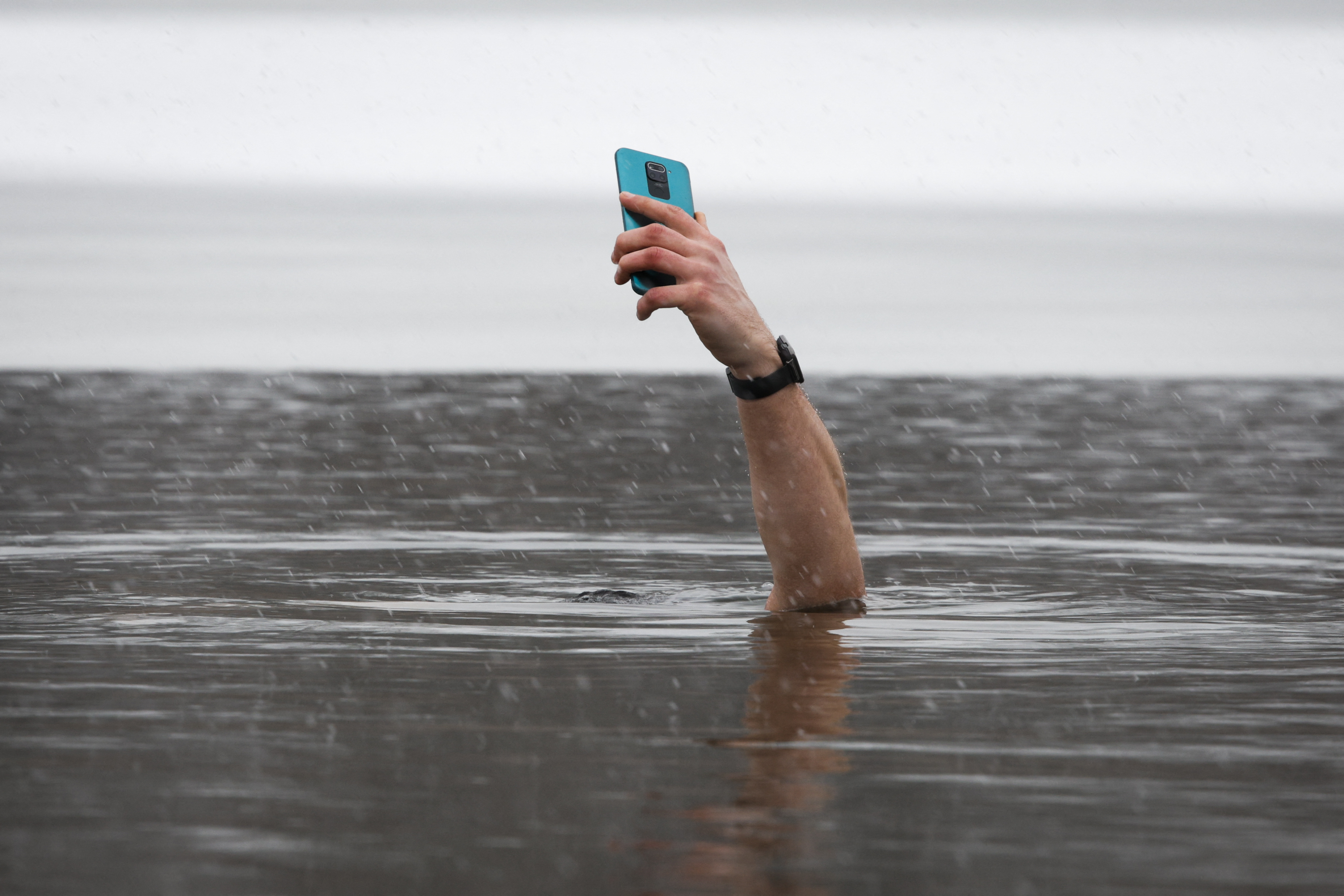 braccio emerge dall'acqua con smartphone in mano